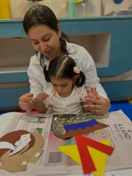 This image captures a sweet moment of collaboration between a mother and daughter during a craft activity at our Rajouri Garden location.