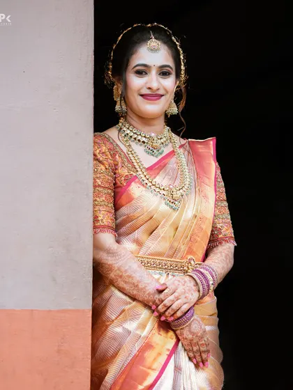 This bride's look is a perfect example of classic South Indian bridal makeup. The focus is on radiant skin, expressive eyes, and a hairstyle that supports the traditional maang tikka.