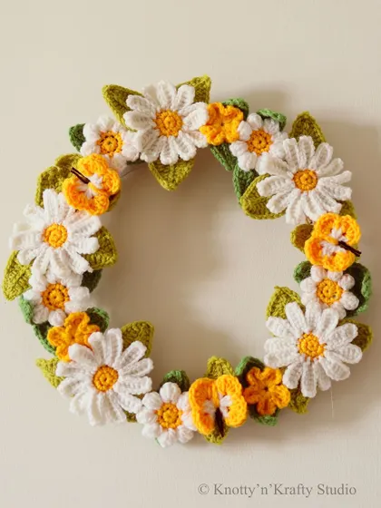A clean shot of the festive wreath against a white wall, highlighting its intricate floral details.