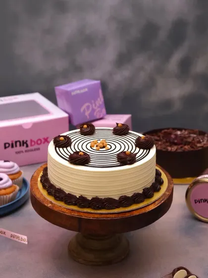 A full view of our signature Butterscotch cake on a wooden stand. The mesmerizing spiral design and crunchy nougat topping make it a centerpiece for any celebration.