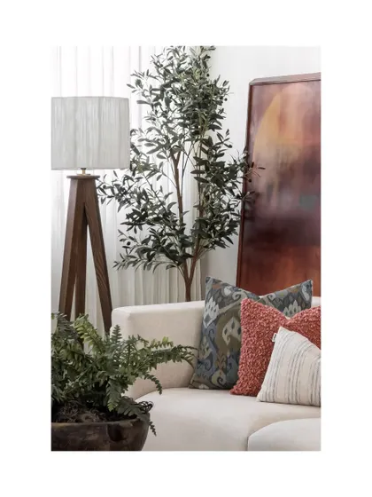 A detail shot of the layered cushions, a tripod floor lamp, and a leaning piece of abstract art. The composition highlights our approach of creating rooms that don't try too hard.