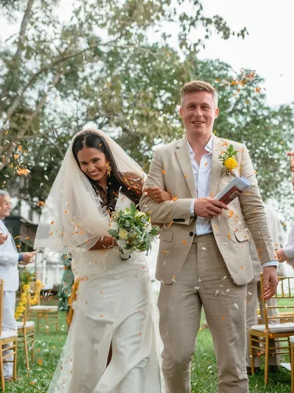 A happy couple walks through a shower of petals after their outdoor ceremony, surrounded by the beauty of nature.