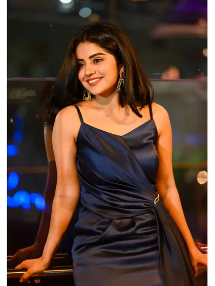 A smiling shot of Pavithra Gowda in the navy satin gown. The soft fabric and elegant draping are perfect for an evening event.