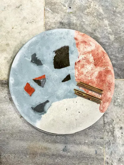 Experimenting with different materials and colors to create exciting new terrazzo tabletops. This sample shows a mix of stone chips and linear elements for a unique, abstract design.