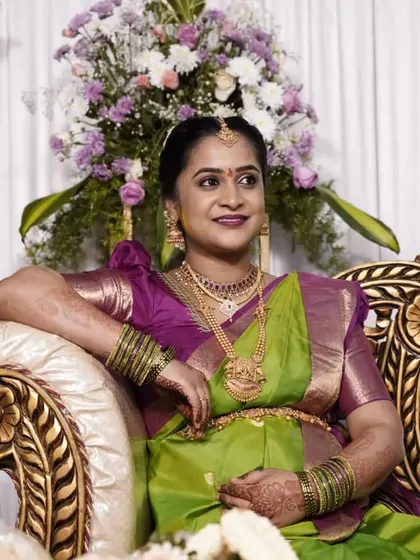 A beautiful mom-to-be at her baby shower. The makeup is kept elegant and glowing, and she looks radiant in her traditional green and purple silk saree.