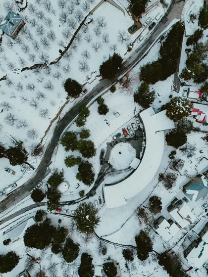 A bird's-eye view of a snow-covered landscape, with a winding road and a uniquely shaped building. Drone photography reveals patterns you can't see from the ground.