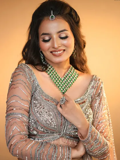 A soft glam look with a beautiful emerald necklace. The eye makeup has a hint of shimmer, and the lips are a natural nude, perfect for an elegant evening.