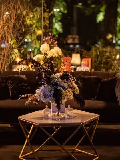 A comfortable lounge setting at the black and gold event, with a central floral piece on the coffee table. This shows how we carry the design theme through every part of the event space, ensuring a cohesive experience.