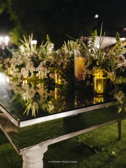 The reflection of the floral arrangements on the mirrored table creates a sense of depth and luxury.