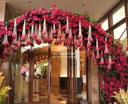 A stunning floral arch of vibrant bougainvillea and hanging jasmine tassels creates a breathtaking welcome for a traditional Haldi ceremony.