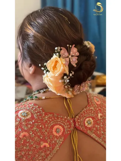 A timeless bun adorned with delicate roses, baby's breath, and whimsical butterflies for a truly magical bridal look.