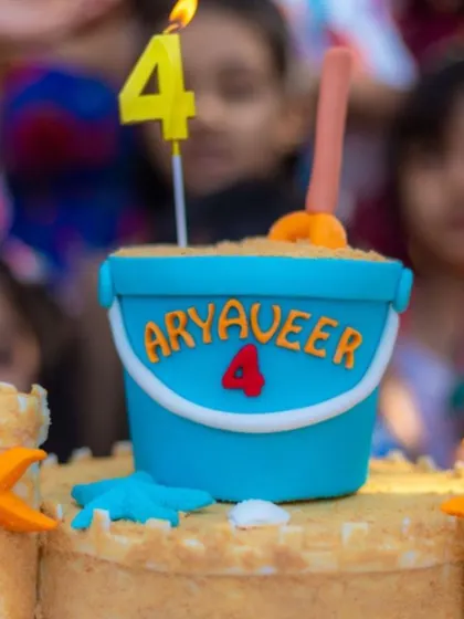 A close-up of the sandcastle cake, showing the bucket and spade topper.