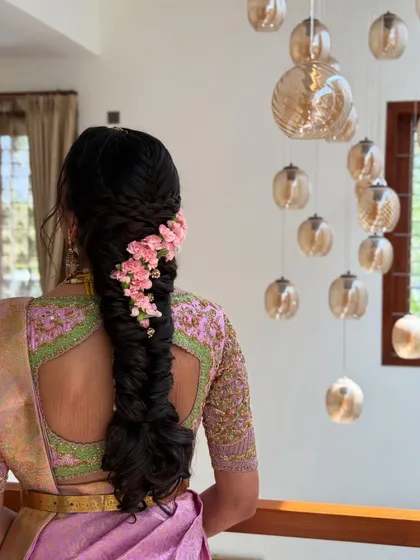 A beautiful shot of the fishtail braid with pink flowers, captured against a modern interior. This shows how a traditional braid can look contemporary and chic.