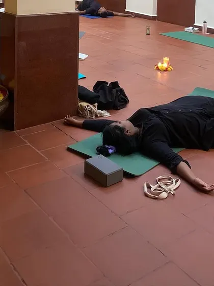A view of participants in a reclined butterfly pose during a workshop. Using props like blocks and pillows helps the body to relax and the hips to open gently.