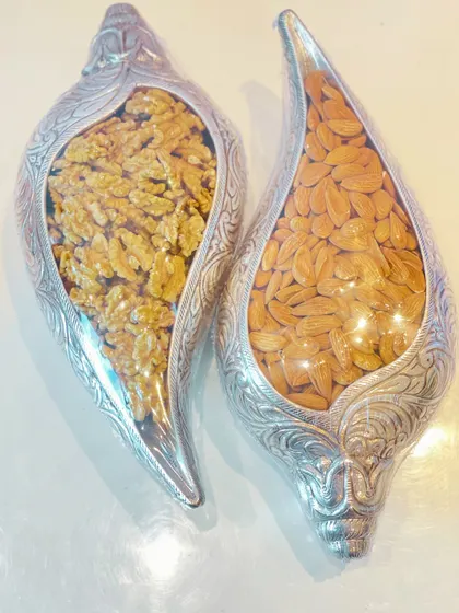 A top-down view of the ornate silver dry fruit containers, showcasing the intricate design and the quality of the almonds and walnuts inside.