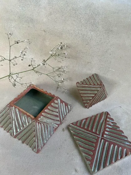 The finished, glazed versions of the pyramid boxes, showing how the glaze highlights the carved textures.