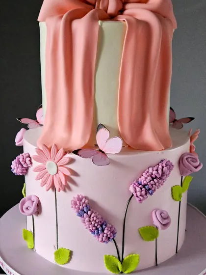 A side view of the tall bow cake, highlighting the graceful drape of the fondant bow.