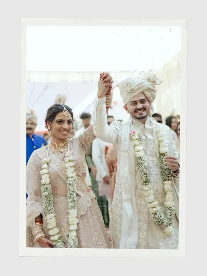 The happy couple walking hand-in-hand after their ceremony. Their joyful expressions and raised hands celebrate the beginning of their new life together.