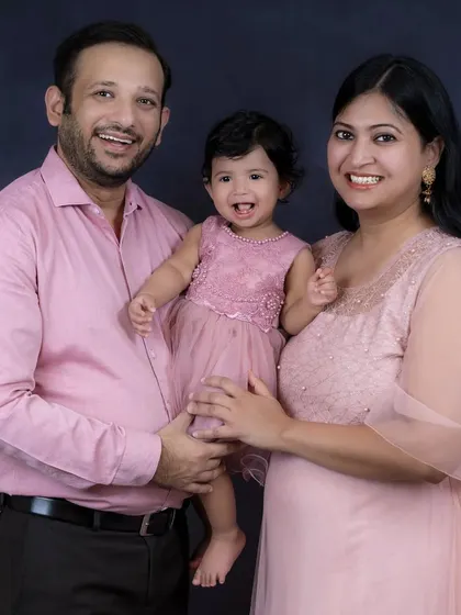 A joyful family portrait with the baby girl laughing as her parents hold her. Their happiness is contagious in this beautiful shot.