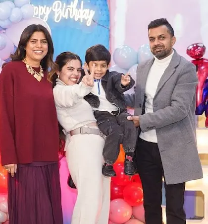 A family and their friends pose for a group photo at a superhero-themed party.