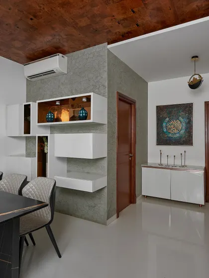 Another perspective of the dining area, showing the textured ceiling and the clean, minimalist crockery unit. The design focuses on a sophisticated palette and functional elegance.