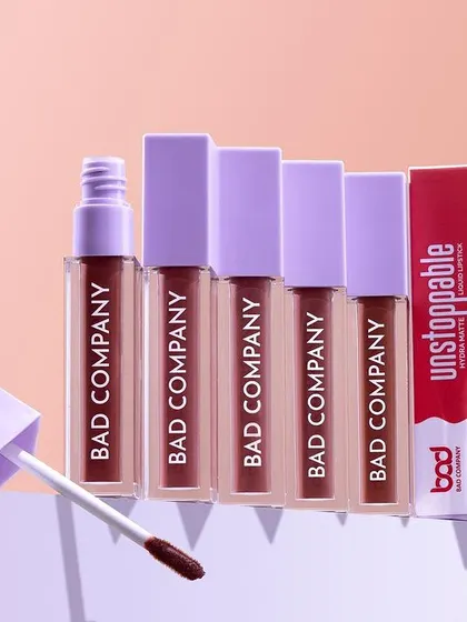 This hero shot for "Bad Company" lipsticks uses geometric blocks to create a modern and clean composition. The arrangement highlights the product packaging and the range of shades available.