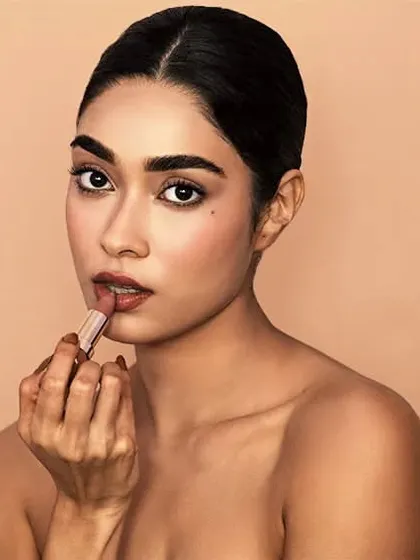 A classic beauty shot demonstrating product application. The clean, neutral background keeps the focus entirely on the model and the cosmetic product.