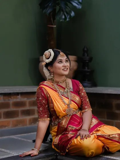 A candid moment of the bride, looking up with a gentle smile. Her makeup is soft and traditional, perfect for the occasion.