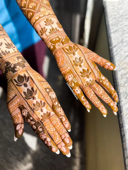 A close-up of the finished lotus-themed mehendi, showing the contrast between the delicate line work and the bold, filled-in lotus flowers.