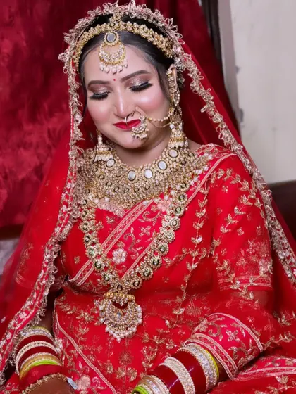 A close-up of this royal bride in red, showcasing the heavy traditional jewelry and the perfectly blended eye makeup with a classic red lip.