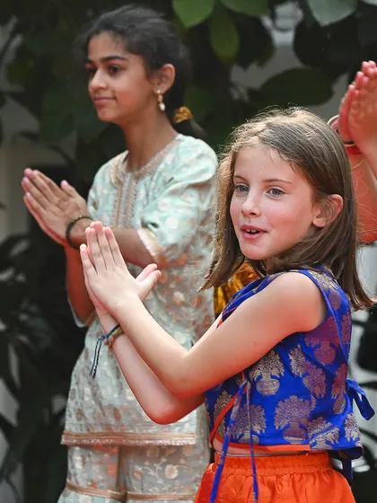A young girl in traditional Indian attire claps along during a performance. Our events are a joyful meeting point for diverse communities in Delhi.