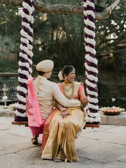 A happy couple enjoying a moment on the floral swing, a classic element in many South Indian weddings that we love to adorn.