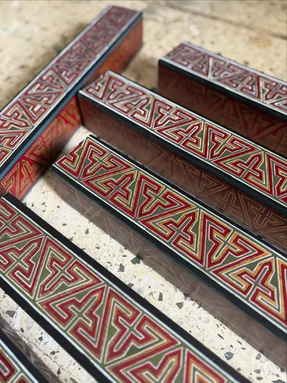 A collection of the hand-painted wooden rafters before installation. This shot highlights the detailed craftsmanship and the rich, warm color palette of the geometric Arabic patterns.