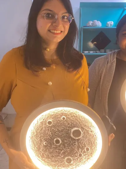 A participant proudly displays the moon lamp she crafted, showcasing her newly learned texture art skills.