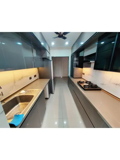 A sleek, parallel kitchen with glossy grey cabinets and a white marble-patterned backsplash. The under-cabinet LED lighting illuminates the workspace and adds a modern touch.