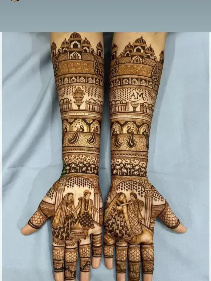 This design tells a story of a royal wedding, with a varmala scene on the palms and the iconic Taj Mahal on the forearms. The couple's initials, 'AM', are subtly woven into the pattern.