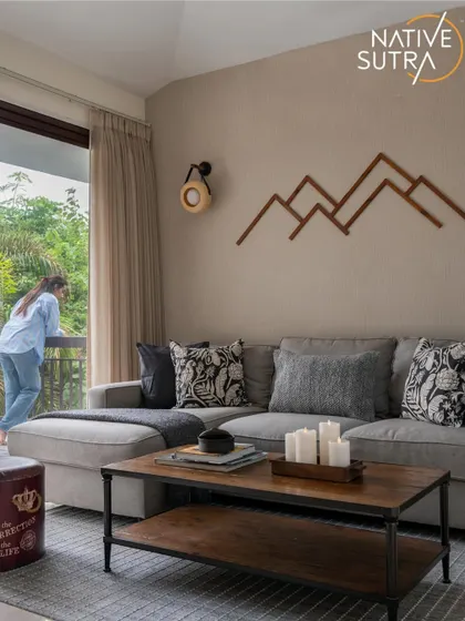 This view captures the connection to the outdoors, with a large window letting in natural light and green views. The space is designed for relaxation, with a comfortable sofa and rustic-industrial coffee table for a warm, inviting feel.