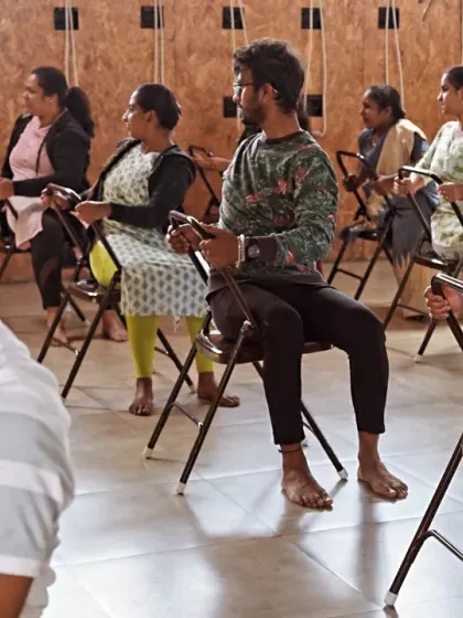 Participants in a workshop at my studio, using chairs to practice twists. This technique helps improve spinal mobility and can be easily replicated at an office desk.