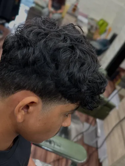 A side view of a textured taper fade. You can see how the hair on top has natural waves and movement, contrasting with the clean, faded sides for a popular men's hairstyle.