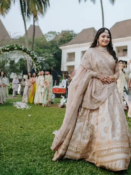 A candid shot of the bride smiling as she walks down the aisle, surrounded by her family and friends at her garden wedding.