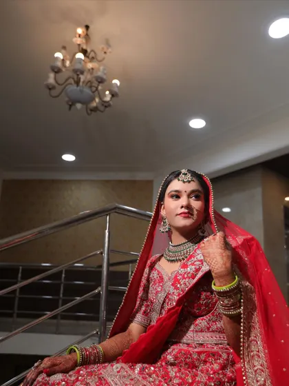 A graceful bridal portrait of the bride sitting on a staircase. The composition uses the elegant surroundings to frame her beautifully, highlighting her poise.