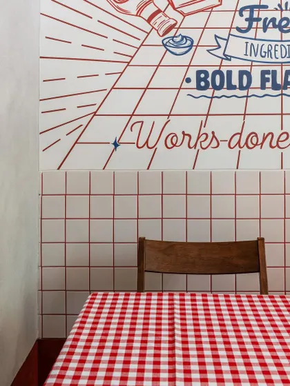 A close-up detail of the seating nook highlights the custom typography and graphics on the wall. The design is clean and minimal, allowing the bold colors and playful text to stand out against the simple grid tile background.
