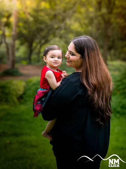 The simple act of a mother holding her child becomes a timeless memory. This outdoor portrait uses the natural greenery and soft light to create a warm and intimate feel.