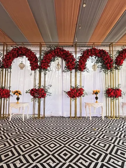 A wider view of the red rose stage decor, showing how the patterned floor and the tented ceiling drapes come together to create a cohesive and stylish look.