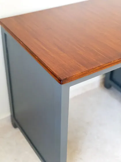 The smooth wooden top of the study desk, contrasting beautifully with the painted grey base.