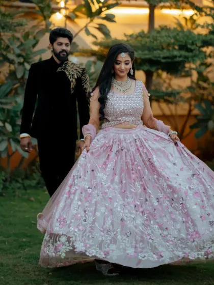 A full-length shot of the bride in her beautiful pastel reception lehenga, looking radiant and happy as she walks with her groom.