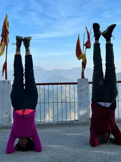 Two practitioners finding balance and strength together in a supported headstand during our Rishikesh retreat.