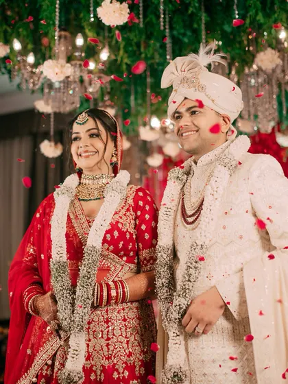 A shower of rose petals blesses the happy couple after their Varmala exchange. This shot is full of joy, color, and celebration.