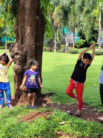 Finding balance together with tree pose during an outdoor class. Leaning on a real tree adds a fun, tangible element to the practice.