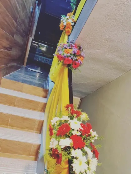 Another angle of our staircase decoration for a housewarming. The combination of soft fabric drapes and colorful floral arrangements adds an elegant and festive touch to the home's interior.